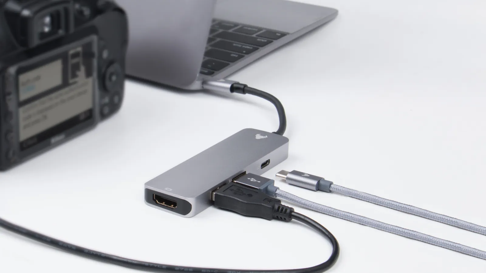 Hub con porte e cavi diversi collegato a un laptop su un tavolo.