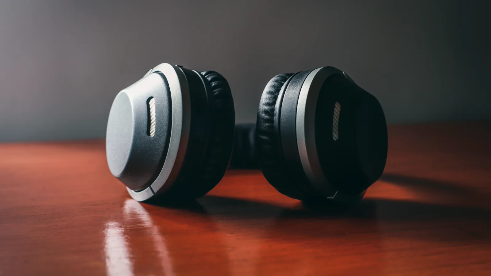 Cuffie Bluetooth nere senza marchio appoggiate su un tavolo in legno.